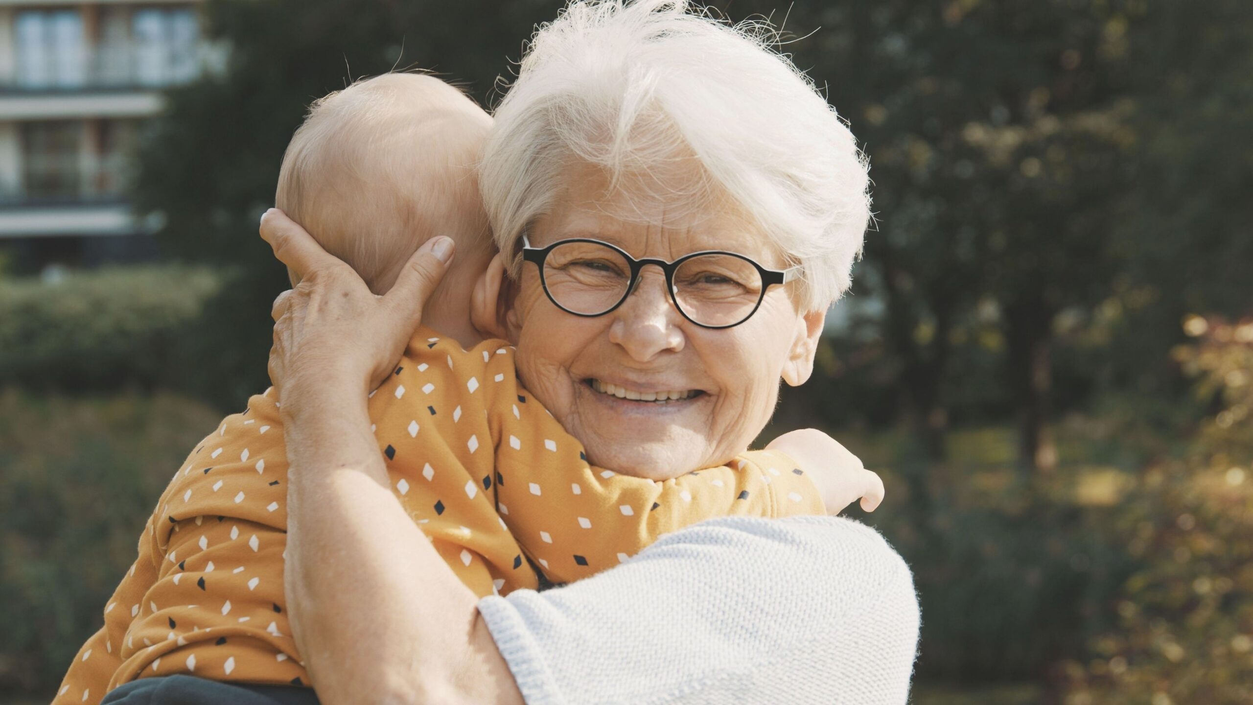 An elderly lady is holding a baby.