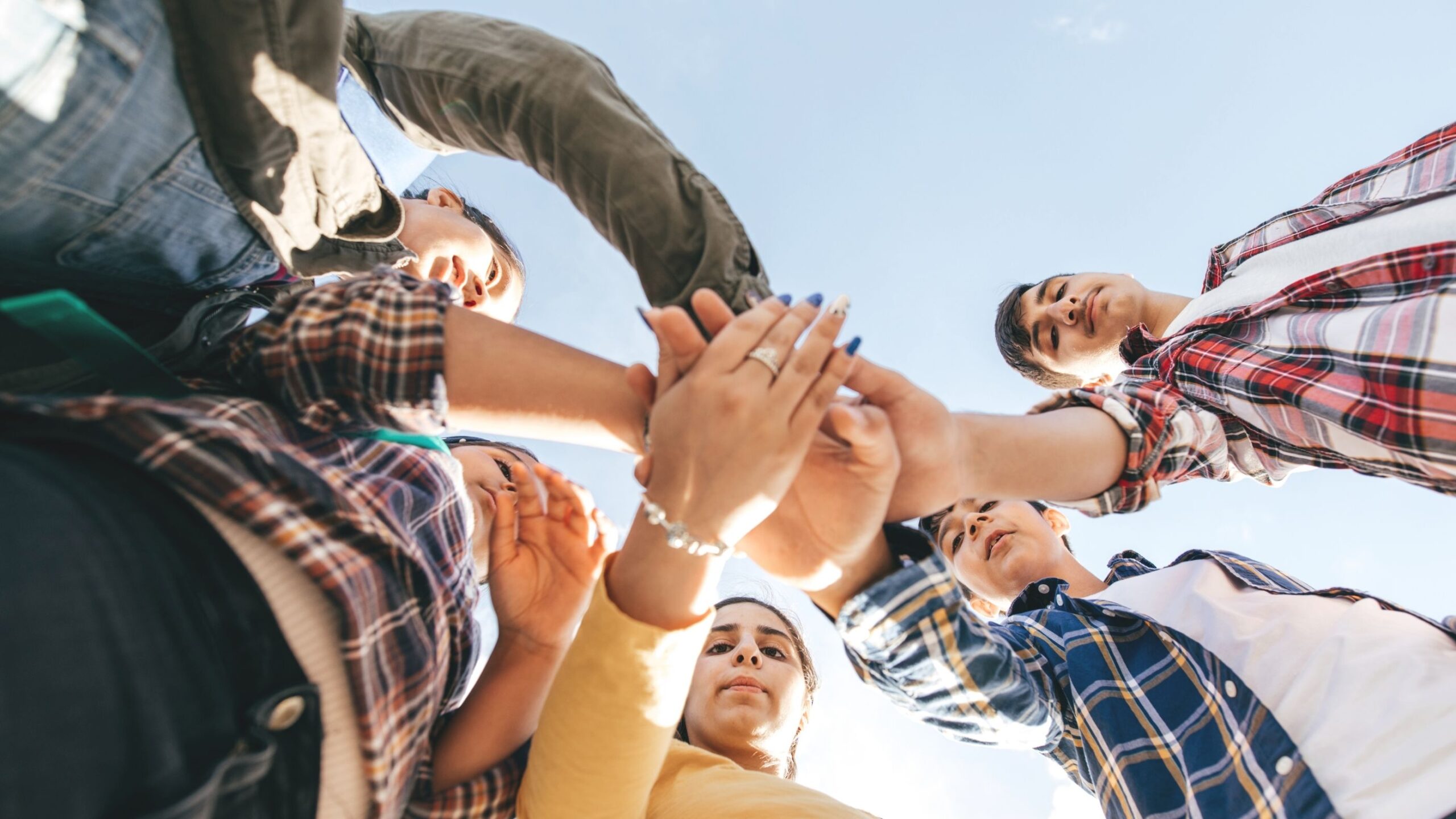 Several people are standing in a circle and they hold their hands in towards the centre.