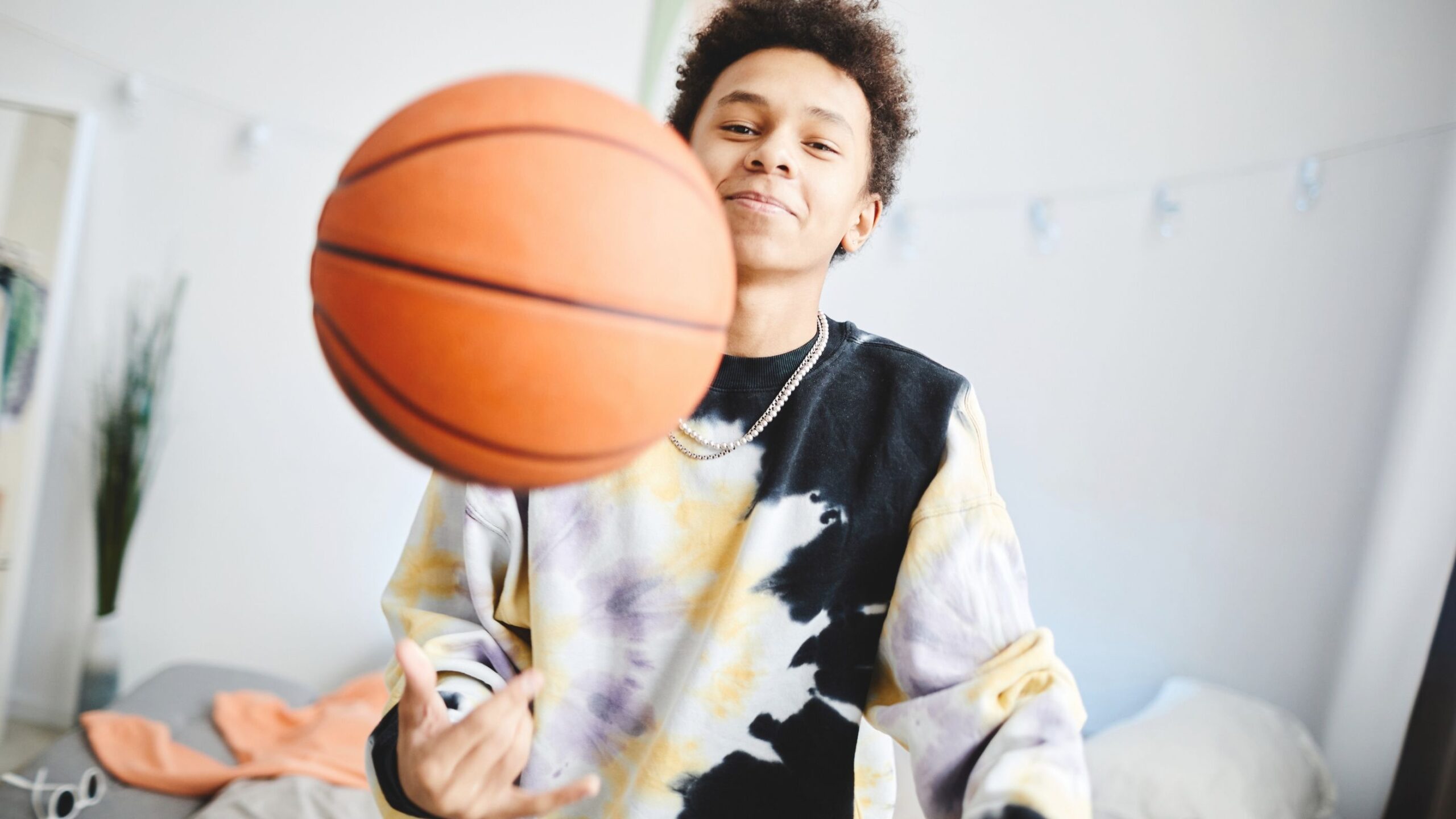 A boy is playing with a basket ball.
