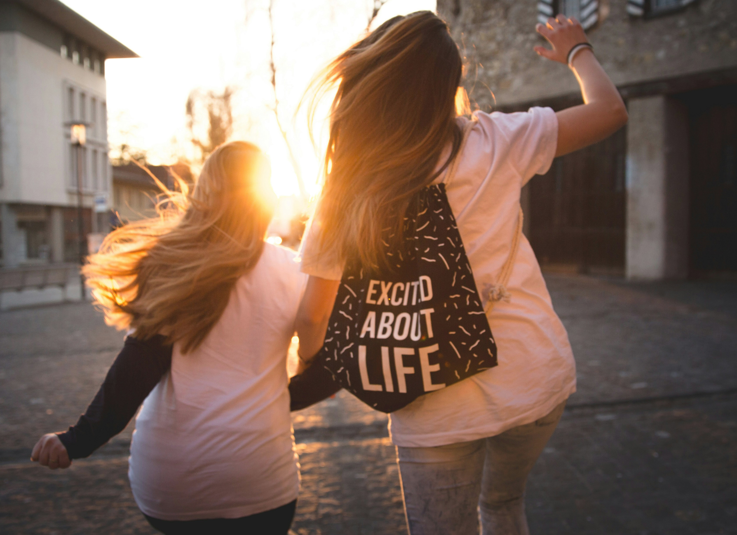 Two girls running towards the sunset.