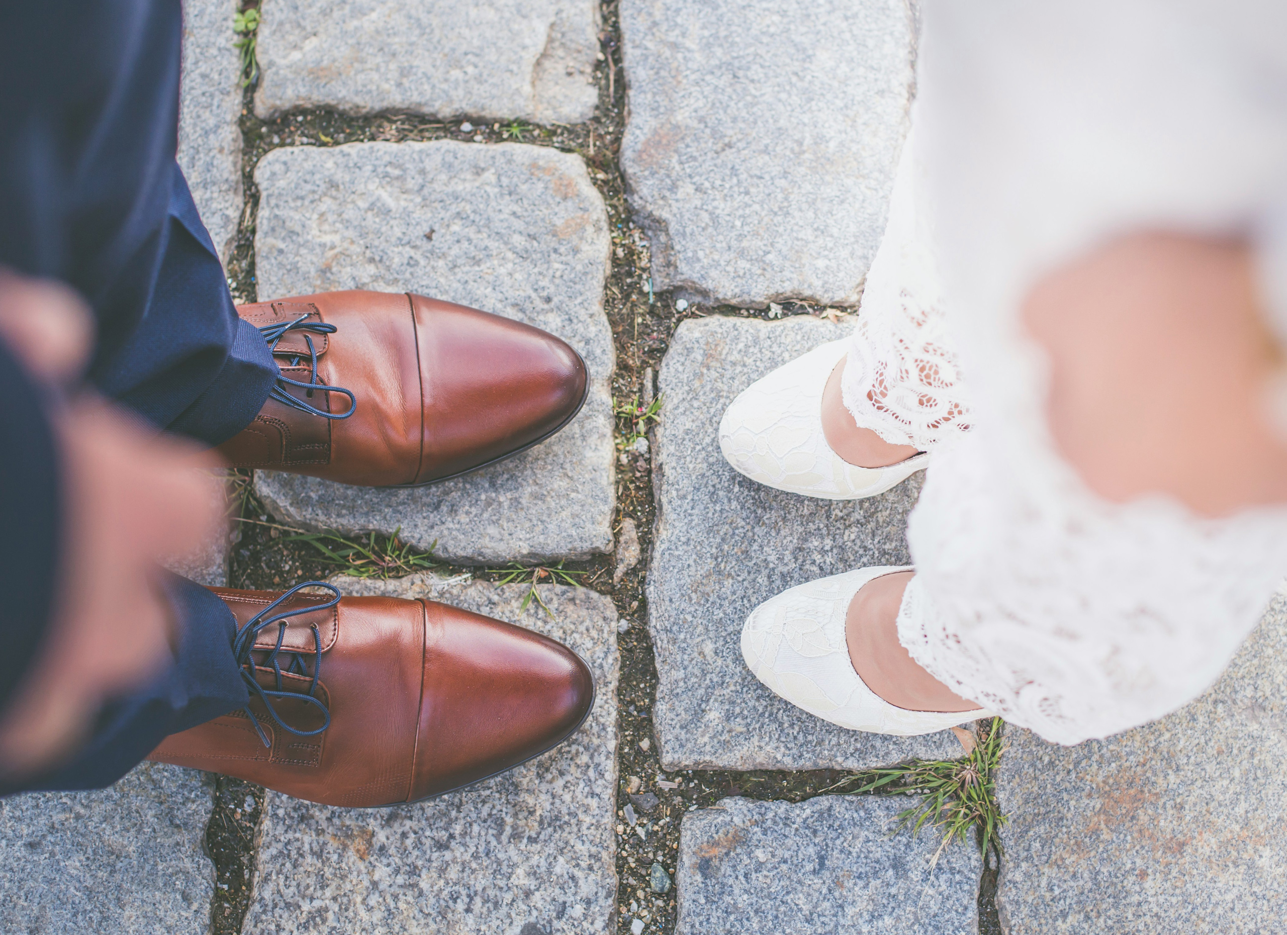 The feet of a bride and groom standing opposite each other.