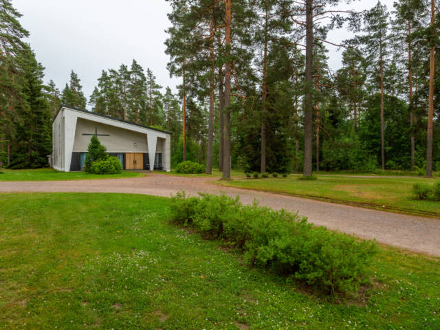 Siunauskappeli taustalla ja edessä nurmikko ja pensas