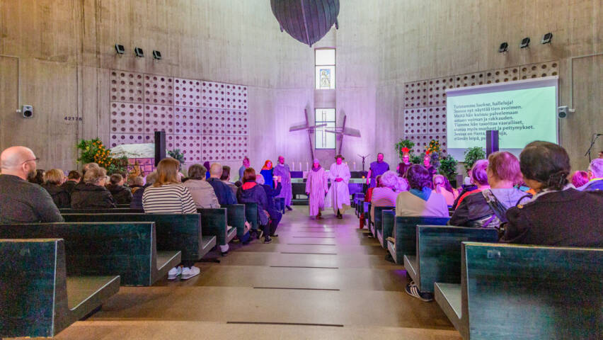 Ylös Jerusalemiin esitys Lauritsalan kirkossa. Katossa roikkuu keluvene ja taustalla alttari ristit. Jeesus ja Maria kävelevät kohti kuvaajaa.