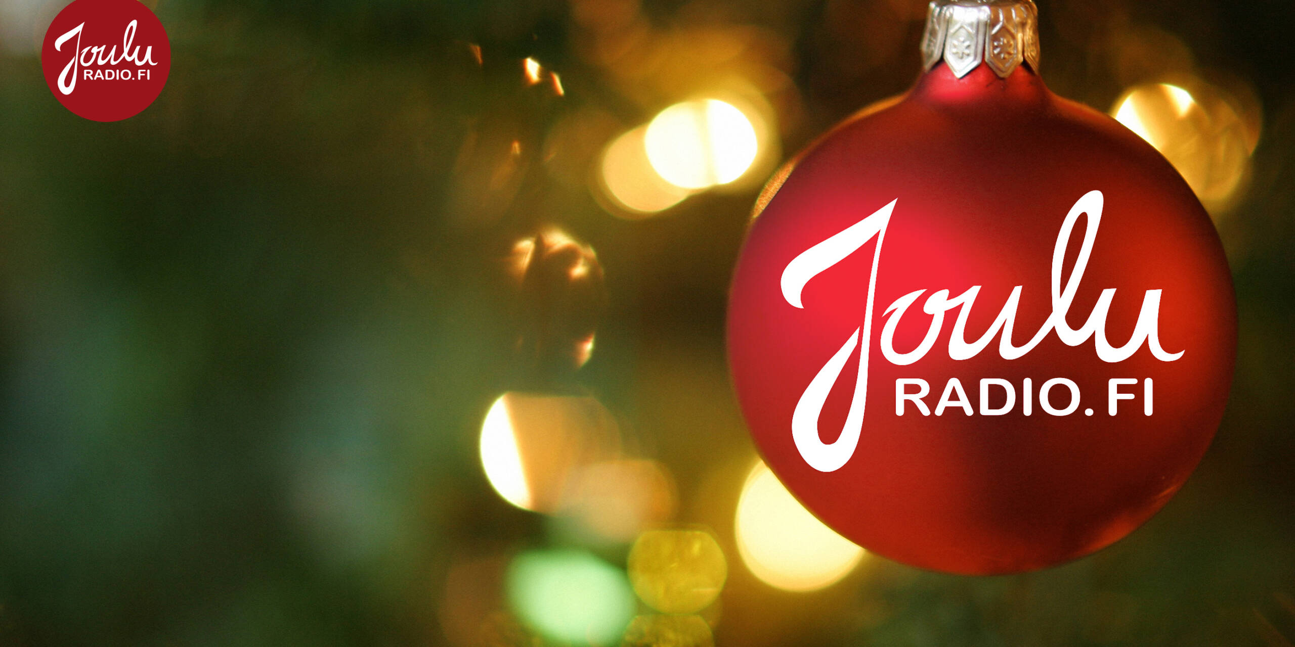 Jouluradio teksti punaisessa kuusen pallossa. Taustalla kuusen kynttilöitä.