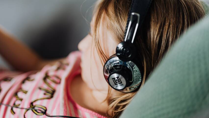 Nainen kuuntelee podcastia sohvalla.